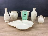 Front view showing the entire collection: six Lenox porcelain items including leaf-shaped dish, planter, vases of varying sizes, all decorated with floral and leaf motifs.