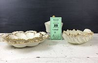 Three cabbage leaf shaped dishes with gold trim and covered footed dish behind them.