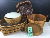 Set of five Longaberger baskets shown together, including one with a white liner and plastic insert, a smaller square basket with floral liner and a large Generosity basket with clear plastic inserts and green stripe detail.