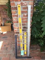 Full view of the two Stanley levels, carpenter's square, and metal ruler showing size and condition.