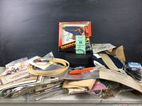 Full view of box contents showing heat tool in original box, embroidery hoops, papers, plastic bags, and cutting tool