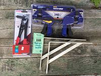 Photo showing all items including Arrow riveter, two Irwin Quick-Grip clamps in original packaging, and pair of shelf brackets on wooden surface.