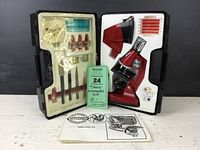 Full view of the Tasco microscope kit open in hard case showing microscope, dissecting tools, slides, instruction booklet, and specimen vials