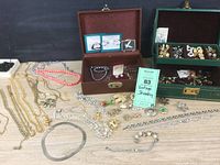 Overview of both jewelry boxes open with assorted necklaces, brooches and earrings laid out