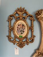 First plaque full view showing ornate gold-tone frame and central porcelain relief with seated figures.