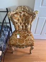 Front view of the Italian provincial style chair showing the carved wooden frame, button tufted back and damask fabric upholstery in golden tones.