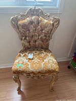 Front view of the Italian provincial style upholstered chair showing carved wooden frame with gold-tone finish and damask patterned fabric upholstery.