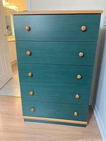 Front view of blue four-drawer dresser with natural wood top and knobs, showing overall appearance and condition.