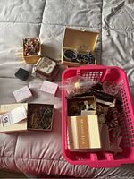 Overview of jewelry boxes, loose jewelry items, and plastic basket containing mixed jewelry and watches.