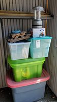 Stacked storage bins containing patio dishes and accessories with battery lantern on top