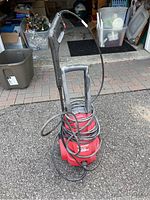 Full view of red electric power washer with handle and cord wrapped around.
