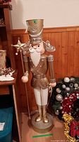 Front view of the tall gold and white nutcracker holding a star-topped staff