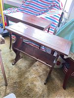 Two wooden end tables shown at an angle to display the top surface and the integrated book rack shelves underneath, visible scratches on surfaces.