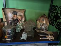 Wide image showing all lot contents: dolls, stacking lunch kit, caravan model, cuckoo clock, metal bell weights