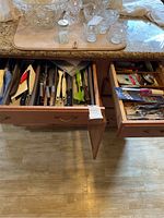 Two drawers filled with various cutlery and kitchen gadgets seen from above on wood floor