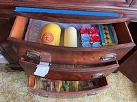 Opened drawer showing assorted pillar candles, votive candles in glass holders, and boxes of tealight candles.