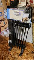 Photo of black Utilities oil-filled electric heater with box for the portable heater placed on top showing size and condition.