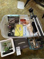 Photo of all items arranged in plastic bin including tripod, router box, stethoscope, hand and foot braces, small tools, draft guard, and mouse.