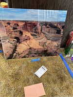 Full shot of photo art on glass showing Canyon de Chelly landscape, placed on carpet with various surrounding items.