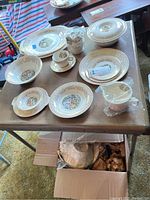 Various Sebring Chantilly china pieces including plates, bowls, cups, saucers, and serving dishes arranged on a table, some still wrapped or boxed.
