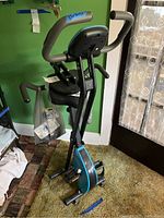 Full view of the folded blue and black Smooth Fitness bike with attached seat, handlebars, and pedals, placed indoors.