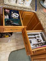 View of two open wooden kitchen drawers showing organized assorted utensils and gadgets.