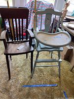 Two wooden vintage high chairs side by side, one dark finish natural wood, one painted light blue with tray, showing wear and scratches.