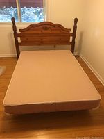 Full view of bed headboard, box spring mattress on metal frame in bedroom setting near window