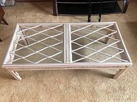 Full view of the cane framed coffee table showing the lattice cane design and removable glass top on carpeted floor.