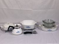 Full lot view showing all CorningWare pieces and accessories arranged on two metal racks