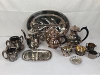 Full view of the entire vintage silver plated tea and coffee service lot with tray and utensils laid out on a plain background.