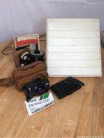 Group photo showing FUJI DL-1000 Zoom camera, Kodak folding camera, Johnson darkroom tank, photography guides, and EZ View slide sorter.