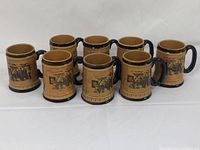 Overall view of 8 amber mugs with black horse and carriage scenes, black handles and decorative trim, arranged in two rows showing difference in height.