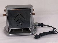 Front angled view of the vintage toaster showing chrome body, wooden knobs, drop side, and power cord.
