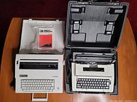 Image showing both Smith Corona typewriters side by side with carrying case open, including accessories like spool packaging.