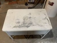 Photo of the metal stand and tabletop surface showing wear and scratches.