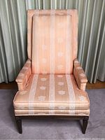 Front view of vintage wingback chair showing full upholstery with floral and stripe patterns.