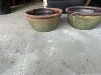 Two large heavy clay pots on ground, showing exterior and rims