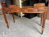 Front view of writing desk showing serpentine front, three drawers, hinged top compartments, brass gallery rail