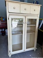 Front view showing three drawers above two glass-paneled doors