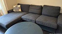 Left-facing chaise sectional sofa in navy blue fabric, IKEA Kivik model, shown in room with round coffee table