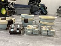 Multiple pieces of Robyn egg blue and cream stoneware arranged on floor, including mixing bowls, pouring bowl, mini roasters, and tagines