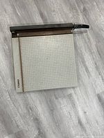 Photo of DAHLE paper cutter showing grid measurement surface and black handle cutter blade