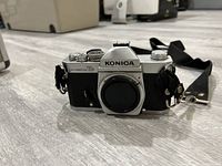 Konica Autoreflex T3 camera body with strap attached, chrome top plate, black body