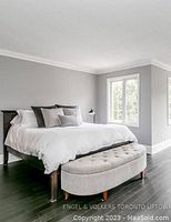 Full view of the queen bed frame assembled with white bedding in a room with dark wood flooring and grey walls. Shows overall size and appearance.