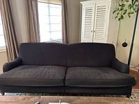 Front view of black three-seat sofa with two seat cushions and continuous back