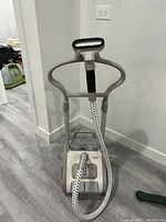 Front view of Rowenta garment steamer with flexible hose and brush attachment, adjustable height pole and wheeled base