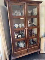 Full front view of teak cabinet showing two glass-panel doors, fixed shelves and two lower drawers
