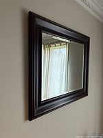 Side angled view of the rectangular mirror showing the depth and dark wood finish of the frame.