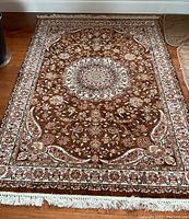 Full view of brown-toned Turkish area rug with floral patterns and fringed edges.